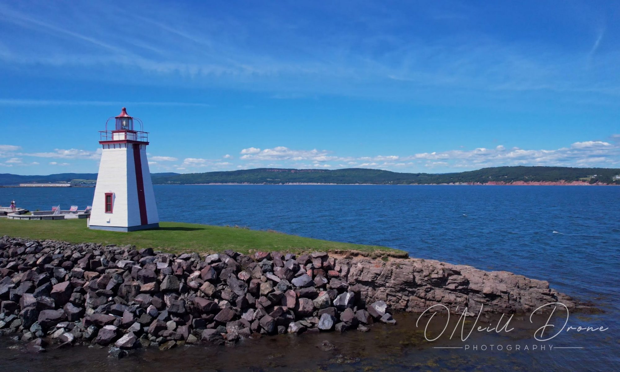 Vue de drone d'un phare blanc au New Brunswick donnant au bord de l'eau